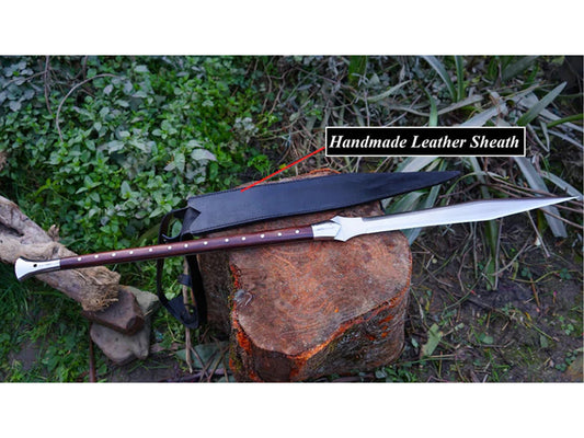 Handmade Viking Spear with 39-inch Carbon Steel Blade and long wooden handle, displayed next to its black handmade leather sheath on a wooden log.