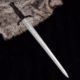 Medieval D2 Carbon Steel sword secured inside its custom dark brown leather sheath on a neutral background.